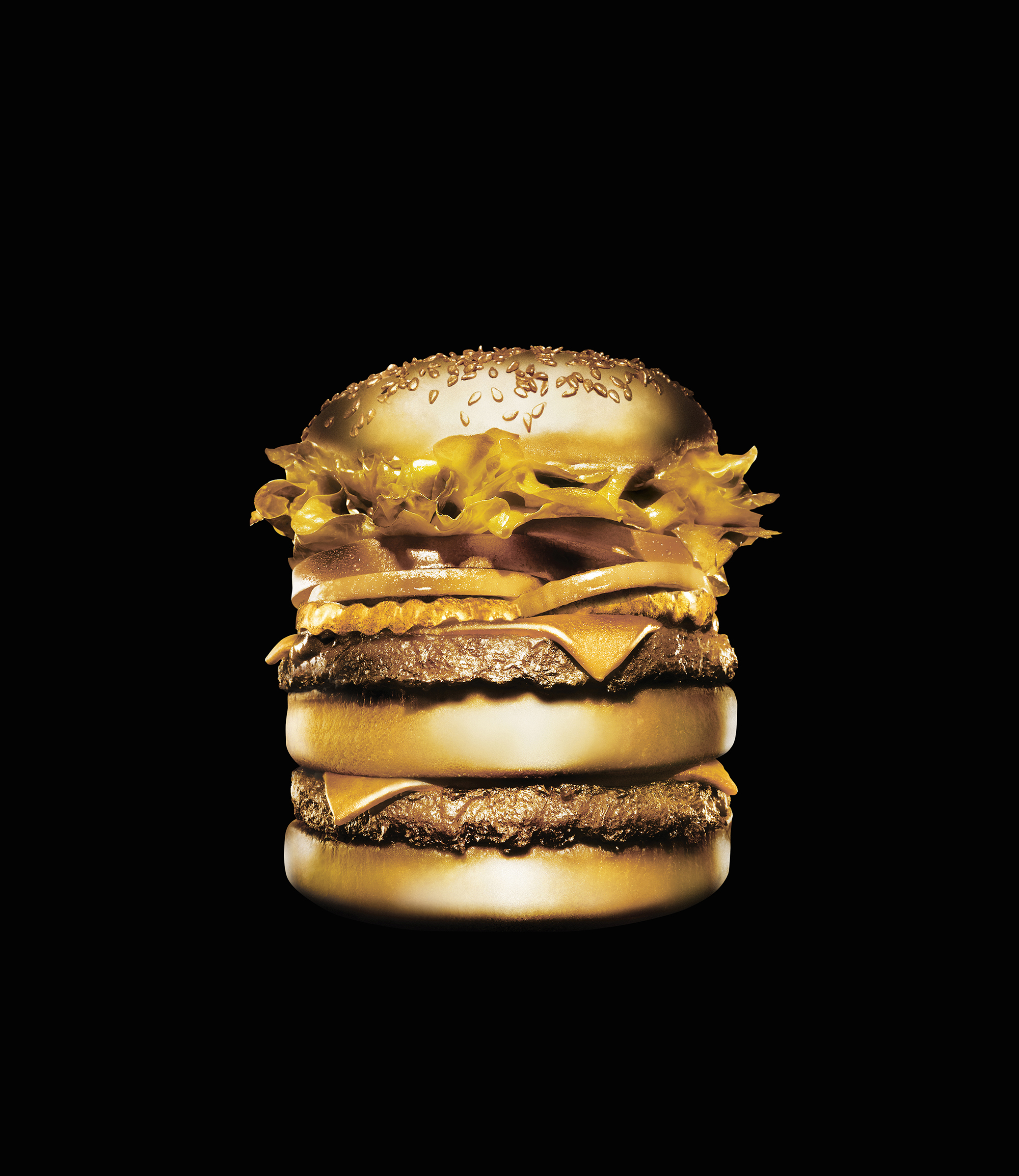 Conceptual still life of a gilded gold hamburger isolated on a black background