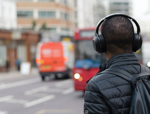 Man wearing headphones while waiting for bus