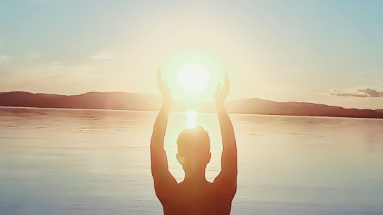 Person raising arms and holding the sun